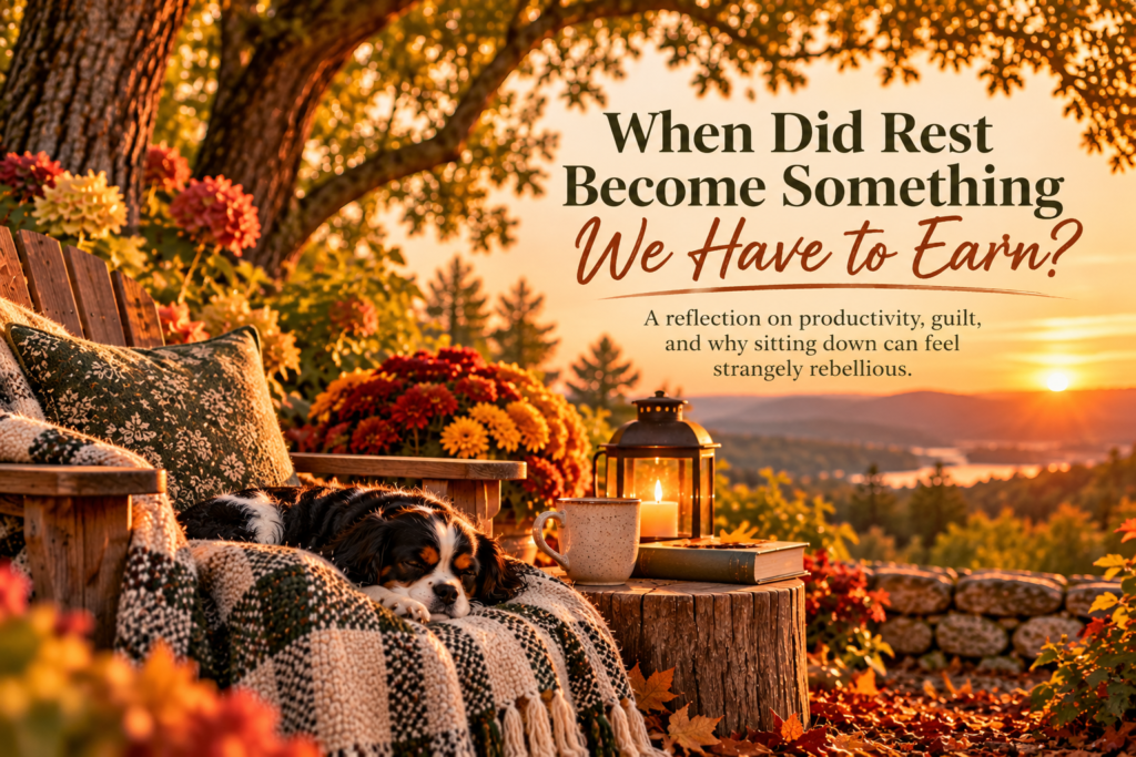 : A tricolor Cavalier King Charles Spaniel sleeps on a cozy blanket beneath autumn oak trees, beside a coffee mug, glowing lantern, and flowers at sunset. Embedded title reads “When Did Rest Become Something We Have to Earn?” with a subtitle about productivity, guilt, and the difficulty of slowing down.