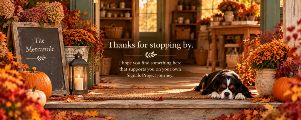 Autumn entrance to The Mercantile with orange chrysanthemums, pumpkins, colorful fallen leaves, and Oreo, a tricolor Cavalier King Charles Spaniel, sleeping beside the doorway. The image reads, “Thanks for stopping by,” with a short farewell message.